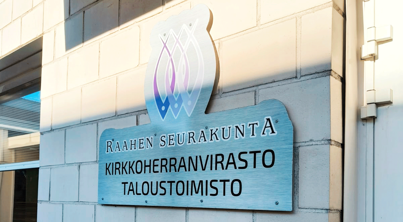 Kuvassa kirkkoherranviraston ja taloustoimiston kylttiä käyntioven vieressä.